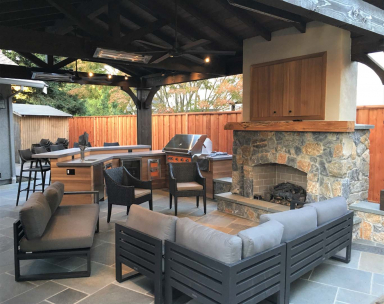 Outdoor pavilion with couches, a bar, fireplace, bbq, television, and more.