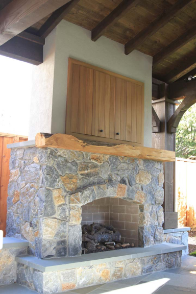 Fireplace in an outdoor pavilion with a shelf and cupboard for a television