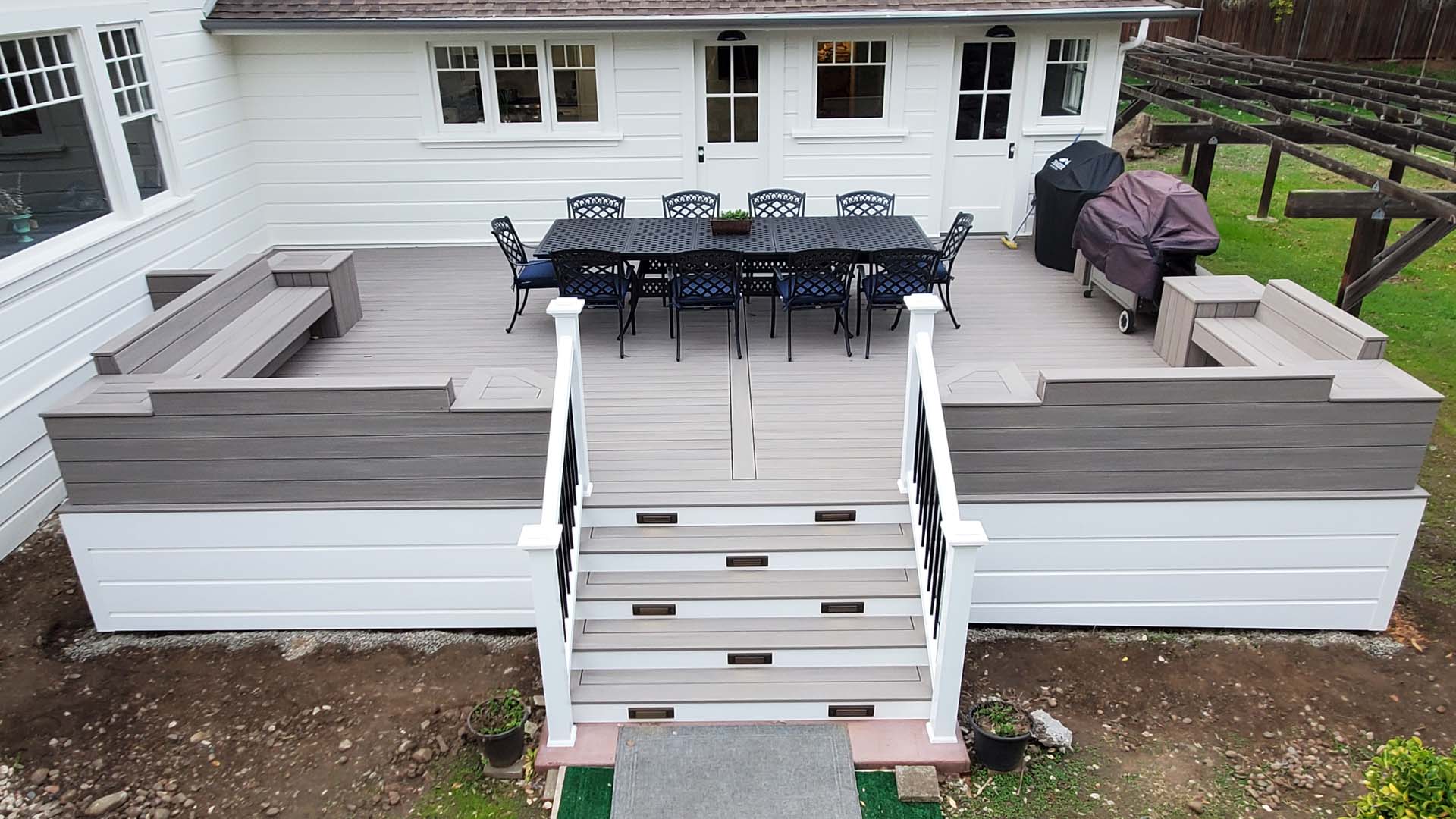 Beautiful new patio deck with built in seats, furniture, and a bbq
